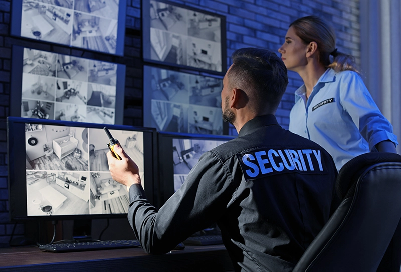 Security officers reviewing surveillance footage on multiple monitors.