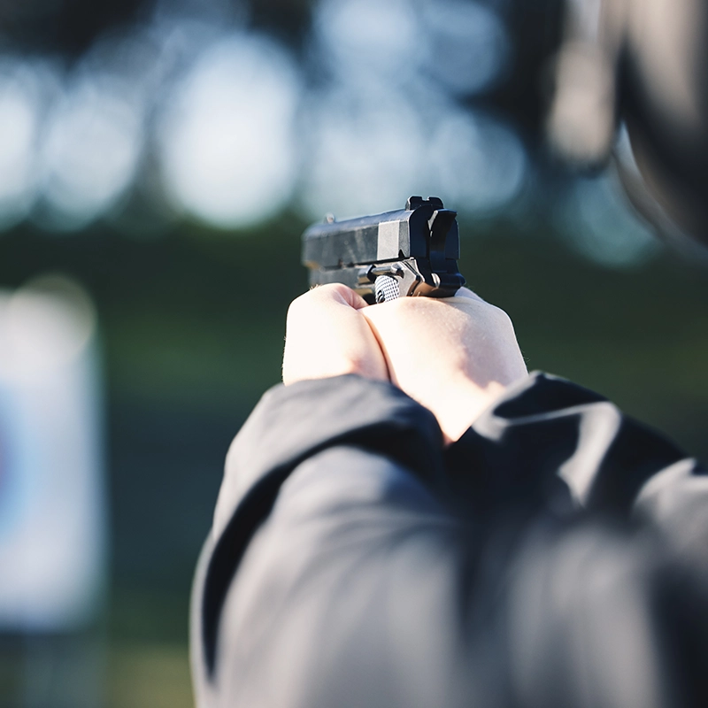 Closeup of man holding gun pointed at target